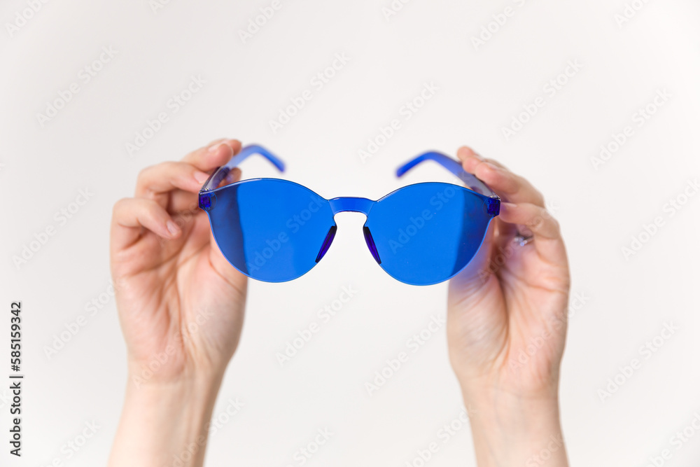 Fototapeta premium The woman's upper hand held up a blue plastic glasses