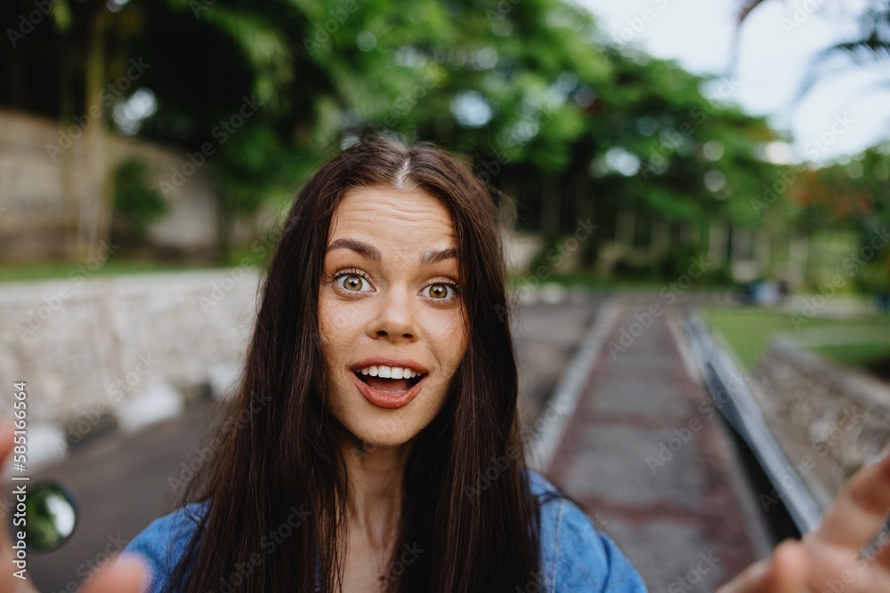 Portrait of a woman brunette smile with teeth walking outside against a backdrop of palm trees in the tropics, summer vacations and outdoor recreation, the carefree lifestyle of a freelance student. Portrait of a woman brunette smile with teeth walking outside against a backdrop of palm trees in the tropics, summer vacations and outdoor recreation, the carefree lifestyle of a freelance student.