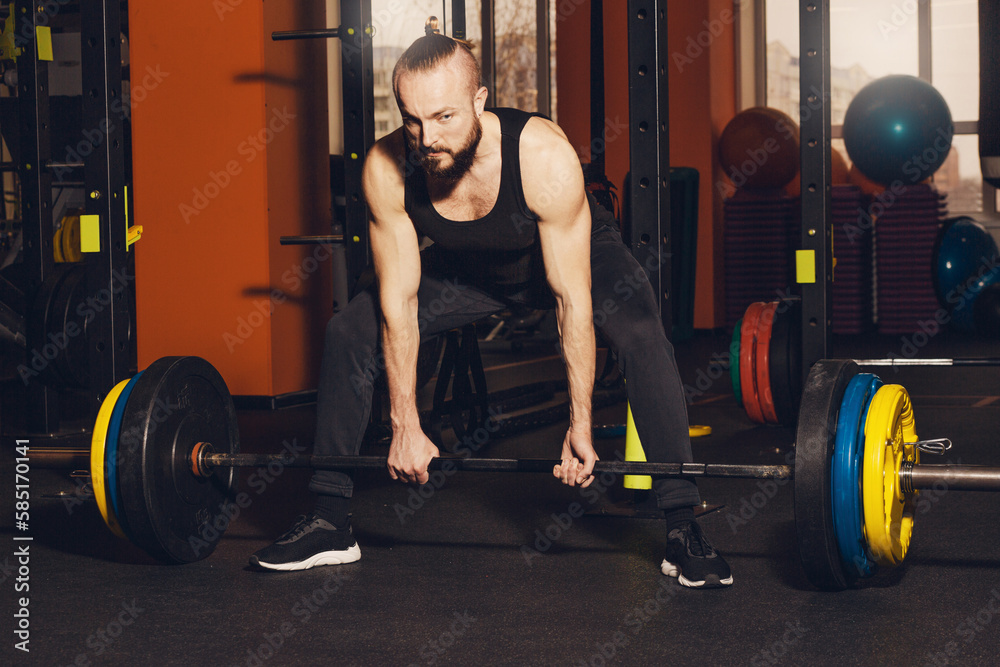 A man of athletic build is preparing to perform an exercise with a barbell.