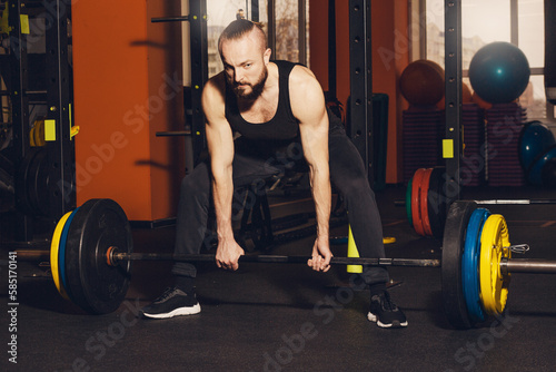 A man of athletic build is preparing to perform an exercise with a barbell.