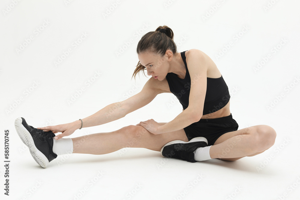young beautiful woman in sportswear stretching legs isolated on white background