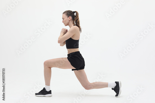 young athletic woman doing lunge exercise isolated on white background, front view
