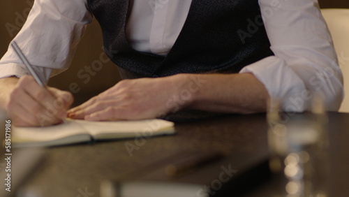 Close-up of male hands and notebook of unidentified young writer. The writer makes notes in a notebook