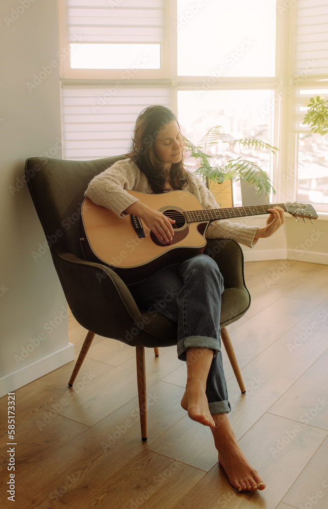 Creative hobby. Talented young female musician sit in armchair alone compose instrumental song using classic guitar. Copy space Creative hobby. Talented young female musician sit in armchair alone compose instrumental song using classic guitar. Copy space