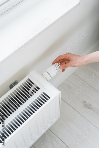 Fototapeta Naklejka Na Ścianę i Meble -  woman regulate thermostat valve of radiator heater