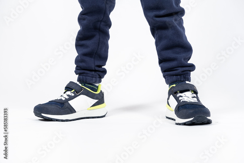 Childrens shoes. Blue kids running shoes sneakers on the legs of a five- or six-year-old boy on a white background.