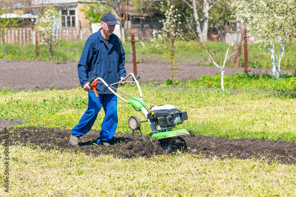 Farmer man plows the land with a cultivator preparing the soil for sowing Farmer man plows the land with a cultivator preparing the soil for sowing