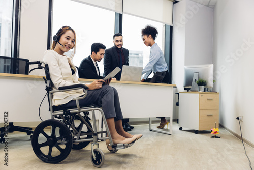 Office workers and woman on a wheelchair in bright office. They are showing a teamwork. Portrait of diverse business team with young woman in wheelchair all smiling at camera in office	