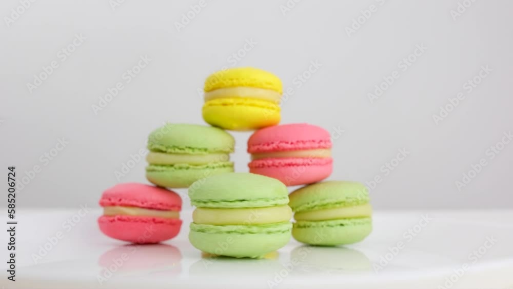 The girl flicks the macaroon with her finger to the side. Macaroon rolls to the side. Art. Natural ingredients. Multi-colored macaroons. Food concept. High quality Colorful tasty macaroons rotating