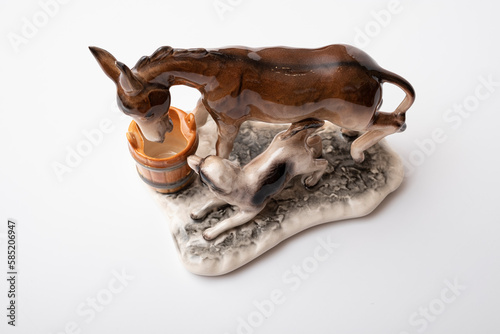 Fototapeta Naklejka Na Ścianę i Meble -  figurine of a donkey that drinks water and next to it a dog teases a donkey