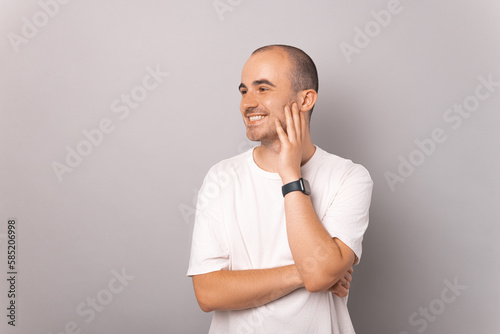 Cheerful handsome man is holding hand on his chin while looking aside.