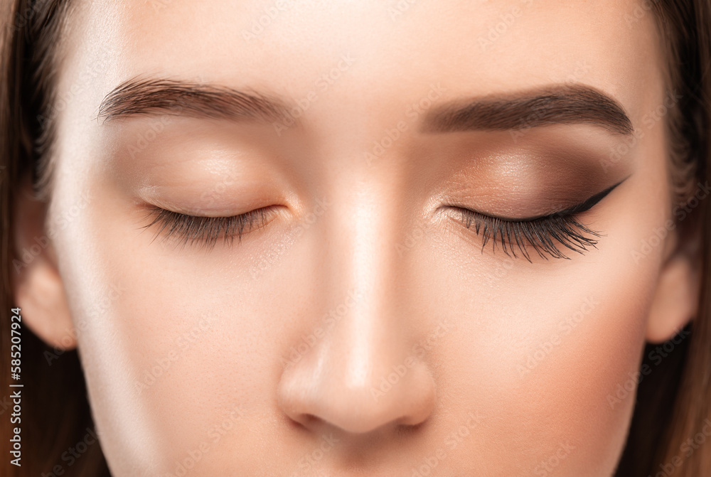 A young beautiful girl removes makeup with a cotton pad and micellar water from her face and eyes.