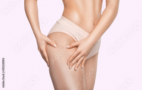 The girl stretches the skin on her leg, showing fat deposits and cellulite. The concept of weight loss and healthy lifestyle.