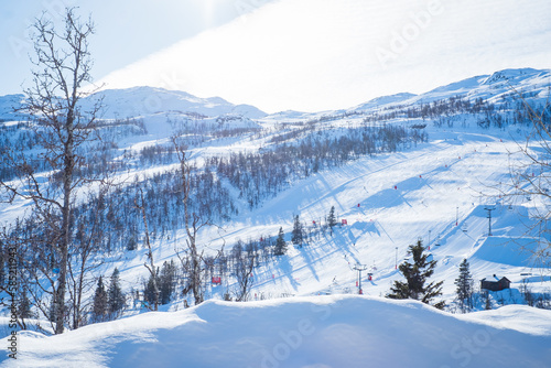 View over ski resort with slopes, chair lifts and majestic snowy mountains during winter day. Hemsedal ski center in Norway.