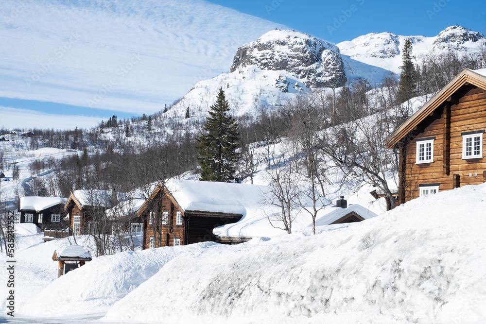 Cozy wooden cabin under snow in the mountains during winter. Ski center accommodation. 