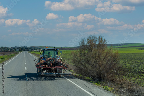 Agricultural machine driving on a paved road next to farmland,rear view.
