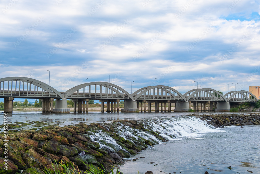 Obraz premium Landscape of the bridge over the river. River flowing with rocks under the road bridge on a blue cloudy sky background. Samsun, Turkey