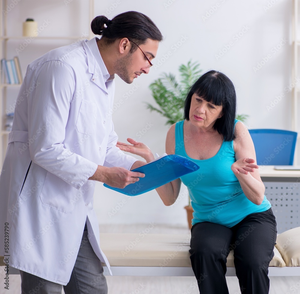 Young male doctor examining old female patient