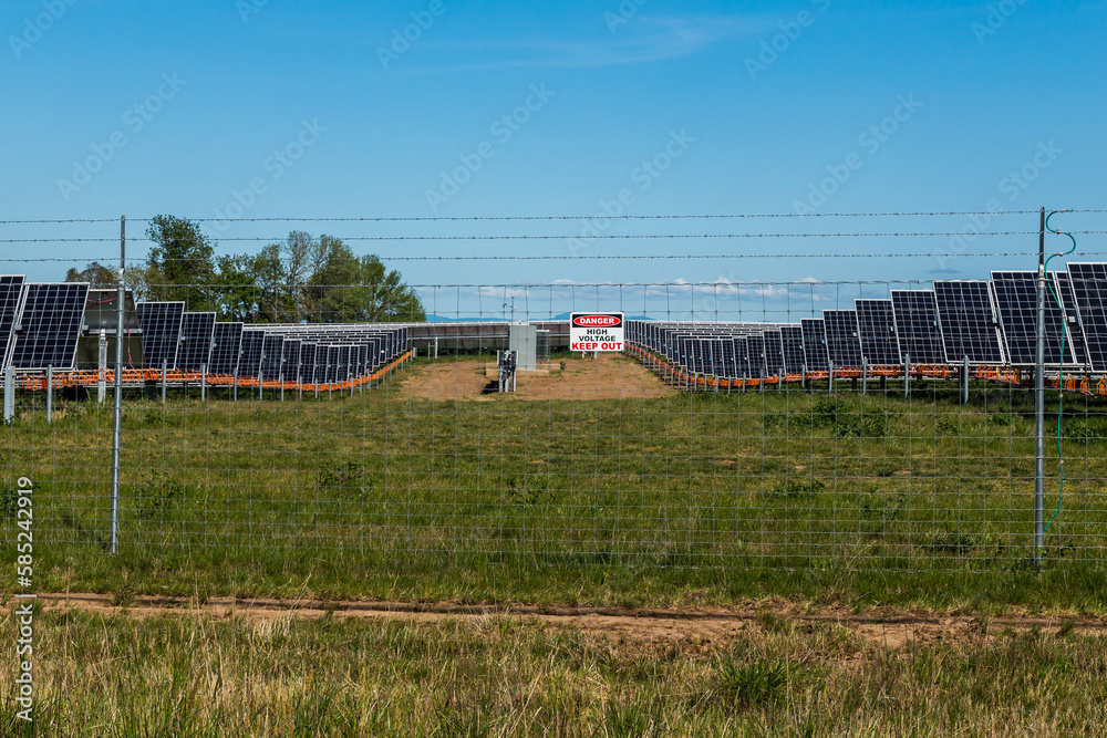Solar panels in a meadow surrounded by barbed wire