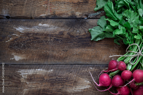 A bunch of fresh red radishes on top of rustic wooden table