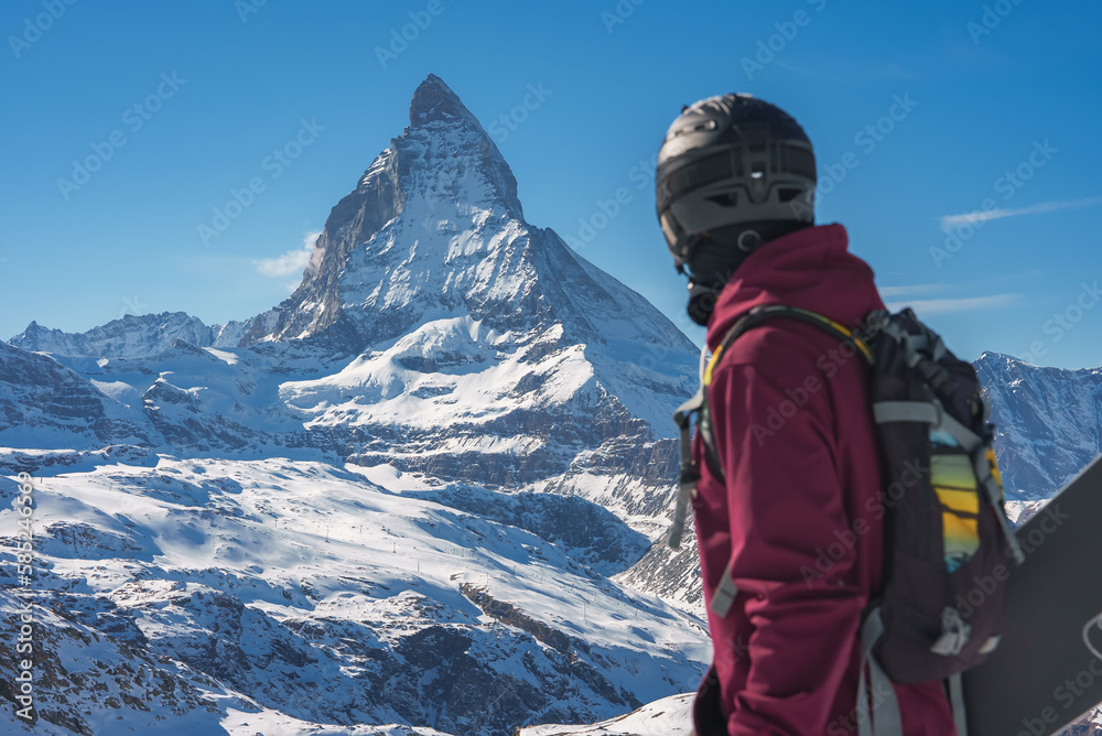 Young snowboarder spending winter holidays in Zermatt, near the famous Matterhorn peak. Male posing in Swiss Alps for the snowboarding season.