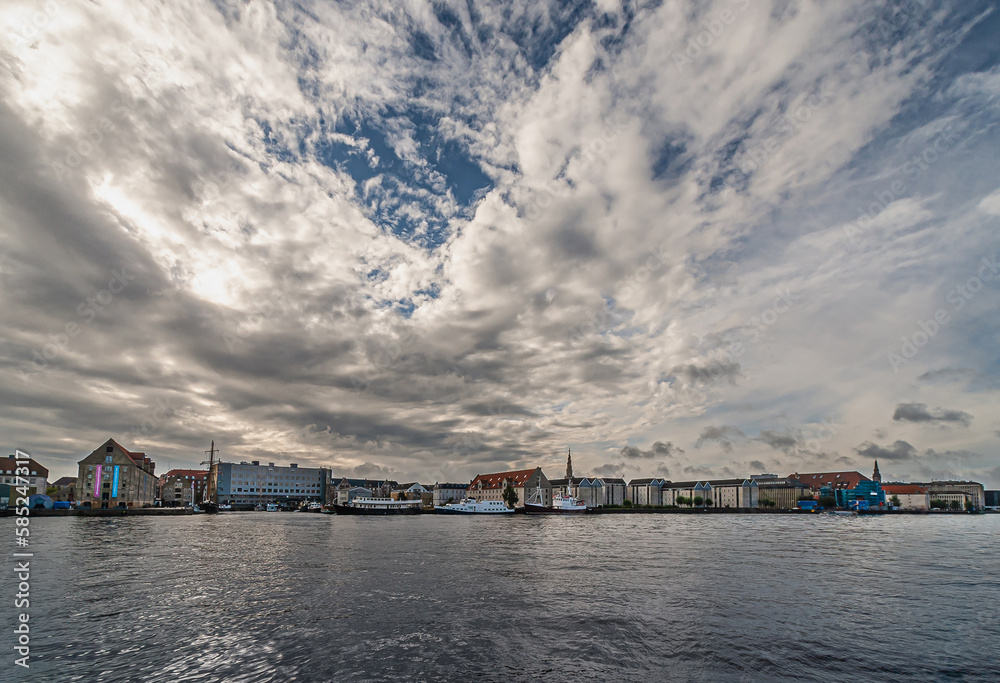 Copenhagen, Denmark - September 13, 2010: Looking east from Nyhavn over Christianshavn shows a panorama of architectural houses, warehouse, offices under heavy blue cloudscape
