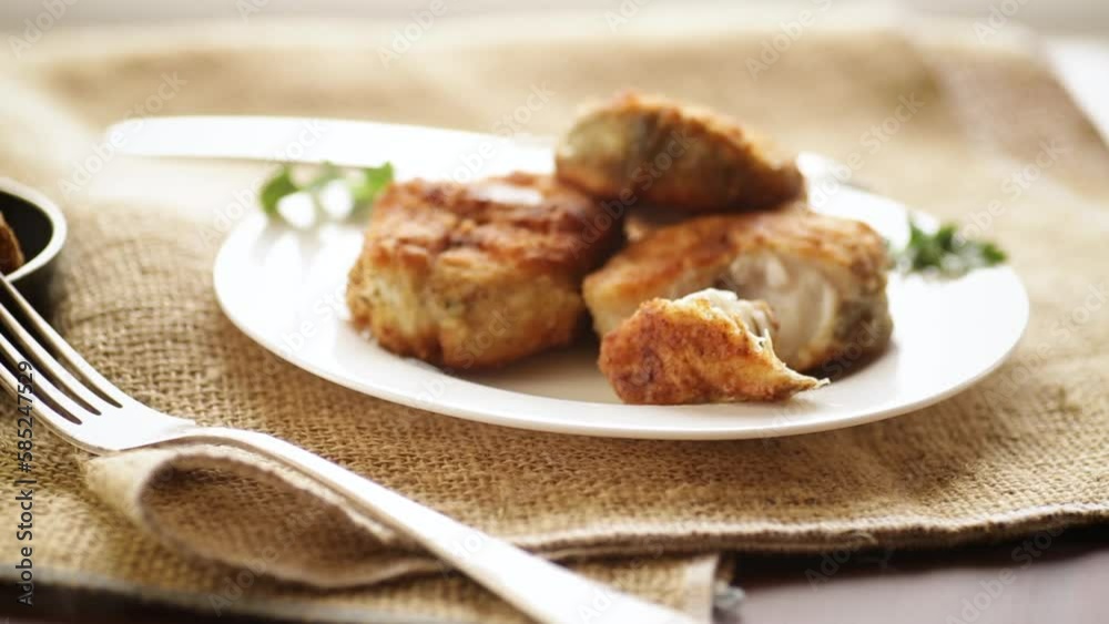 A piece of hake fish fried in a crispy crust, in a plate. A piece of hake fish fried in a crispy crust, in a plate.