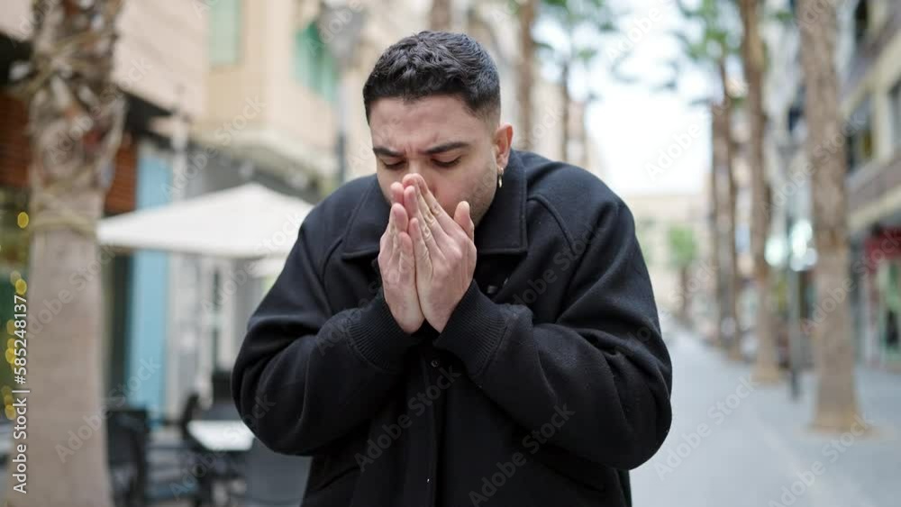 Young arab man blowing air on hands for cold at street Young arab man blowing air on hands for cold at street