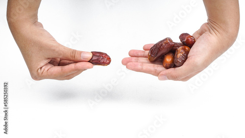 Hand giving a dates fruits or kurma to other hand over white backrgound