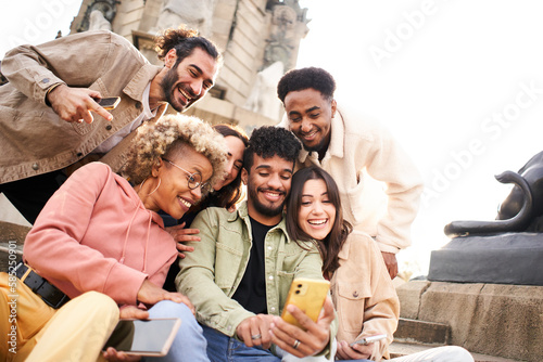 Guy shows his multiracial friends a video on smartphone. Group of people watching something on a mobile or smart device. High quality photo