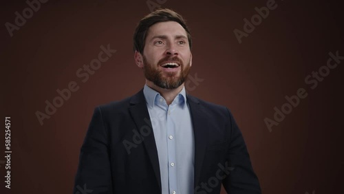 A man in a suit taking off his protetive mask and exhaleing with a big smile. He is in a simple dark brown background. He looks pleased High quality 4k footage photo