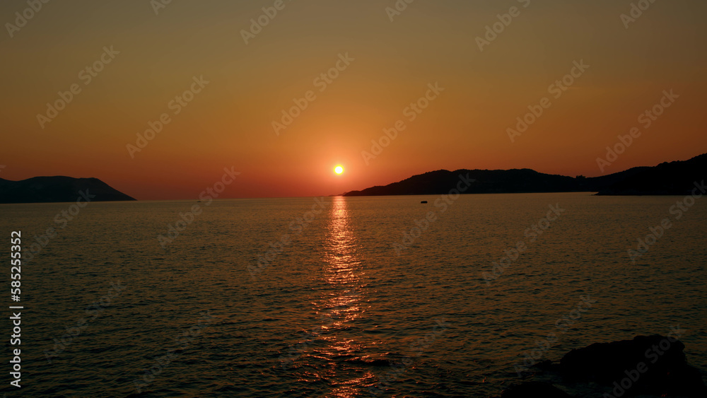 Fiery red sunset over sea between mountains in sea or ocean. Picturesque sunrise with sunny path on water. concept of end of career or its beginning. Natural phenomenon in morning.