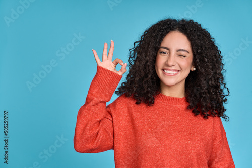 Canvastavla Young happy latin woman student showing ok hand okay sign winking isolated on blue background