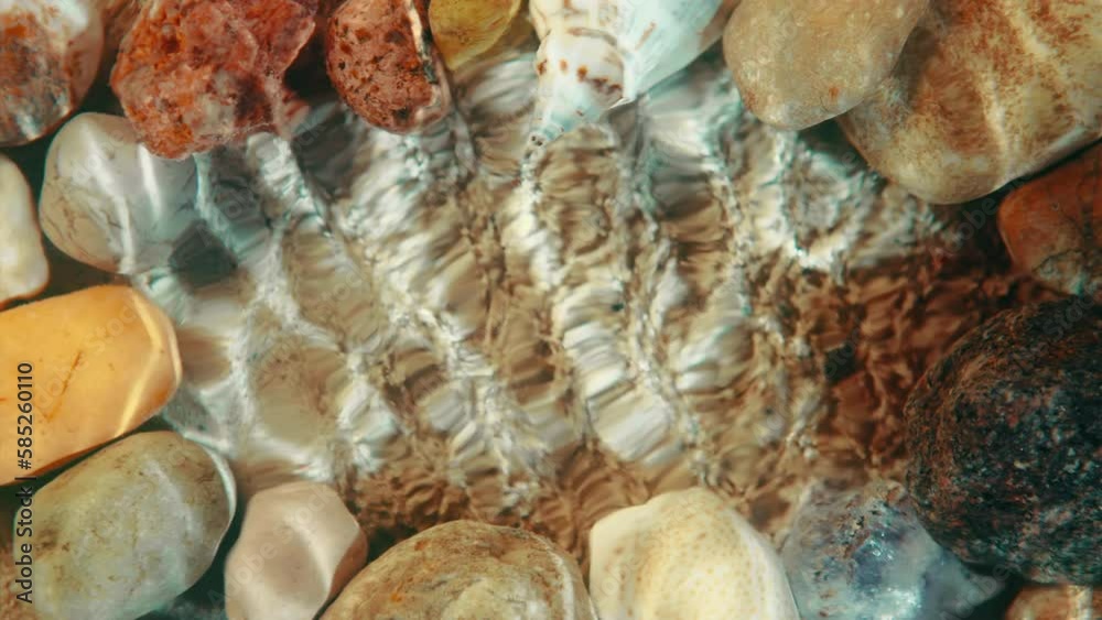 Top down view seabed background, sea floor beach sand ripple of water waves reflection, shells and stones. Yellow sandy bottom surface summer. Underwater seafloor close-up. Place for title or logo
