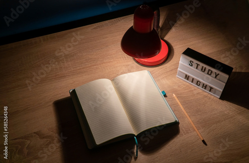 Study concept background. Notepad with blank pages and desk lamp on wooden table high angle view. Study time concept. Selective focus on notebook.