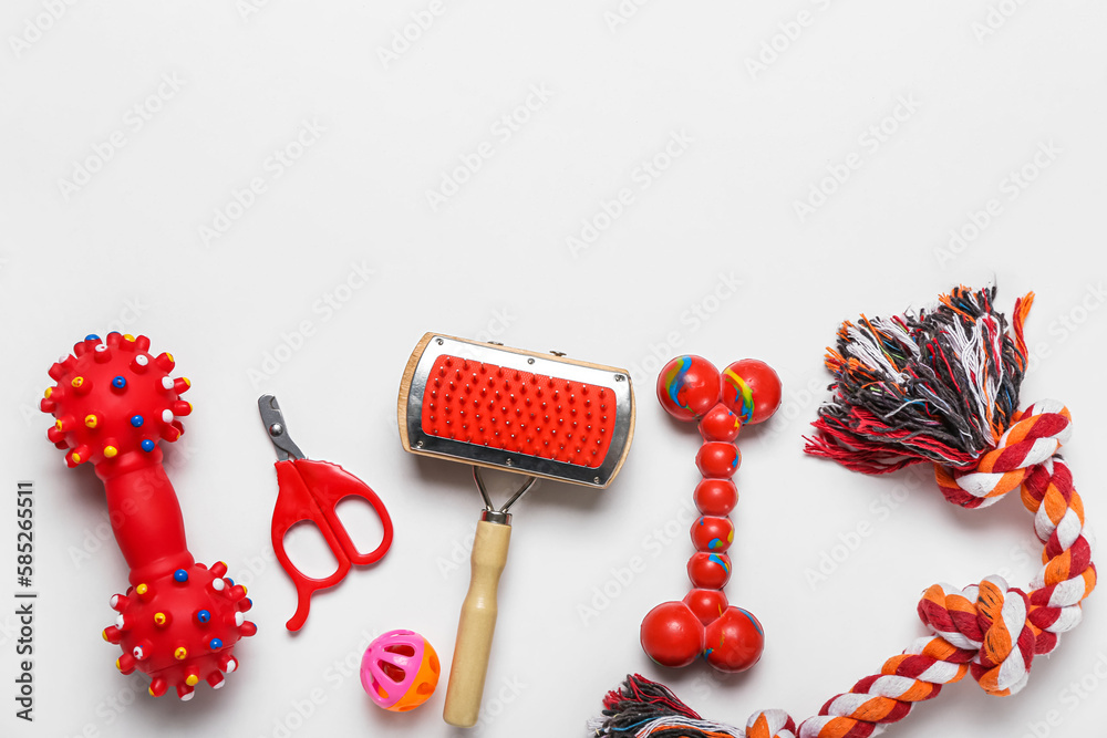 Set of pet toys, grooming brush and nail clipper on light background