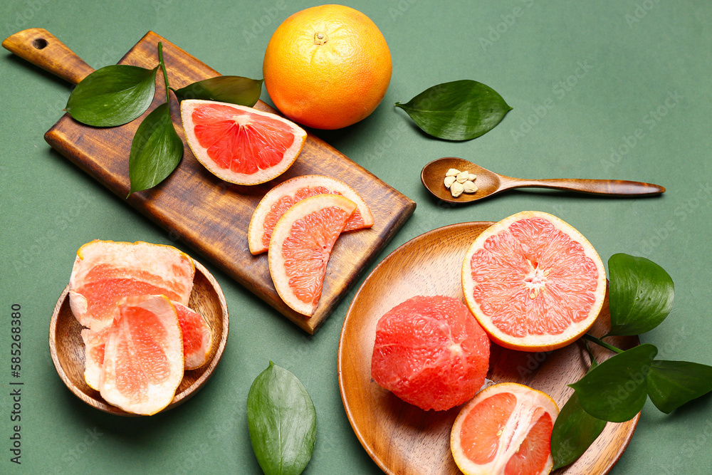 Composition with ripe grapefruits and plant leaves on green background Composition with ripe grapefruits and plant leaves on green background
