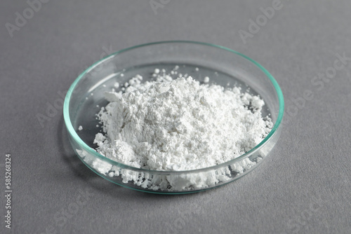 Petri dish with calcium carbonate powder on grey table