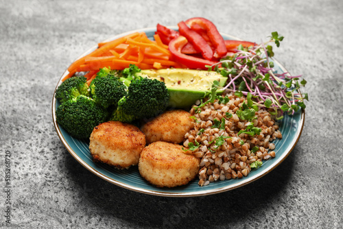 Delicious vegan bowl with cutlets, buckwheat and broccoli on grey table, closeup
