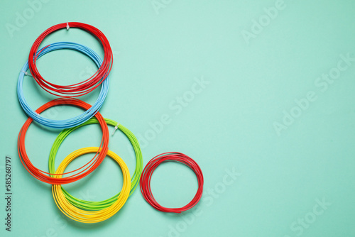 Colorful plastic filaments for 3D pen on turquoise background, flat lay. Space for text