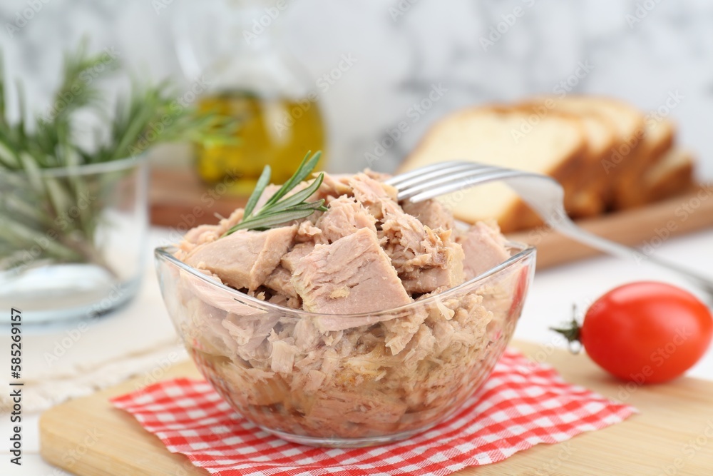 Bowl with canned tuna and rosemary on white table, closeup Bowl with canned tuna and rosemary on white table, closeup