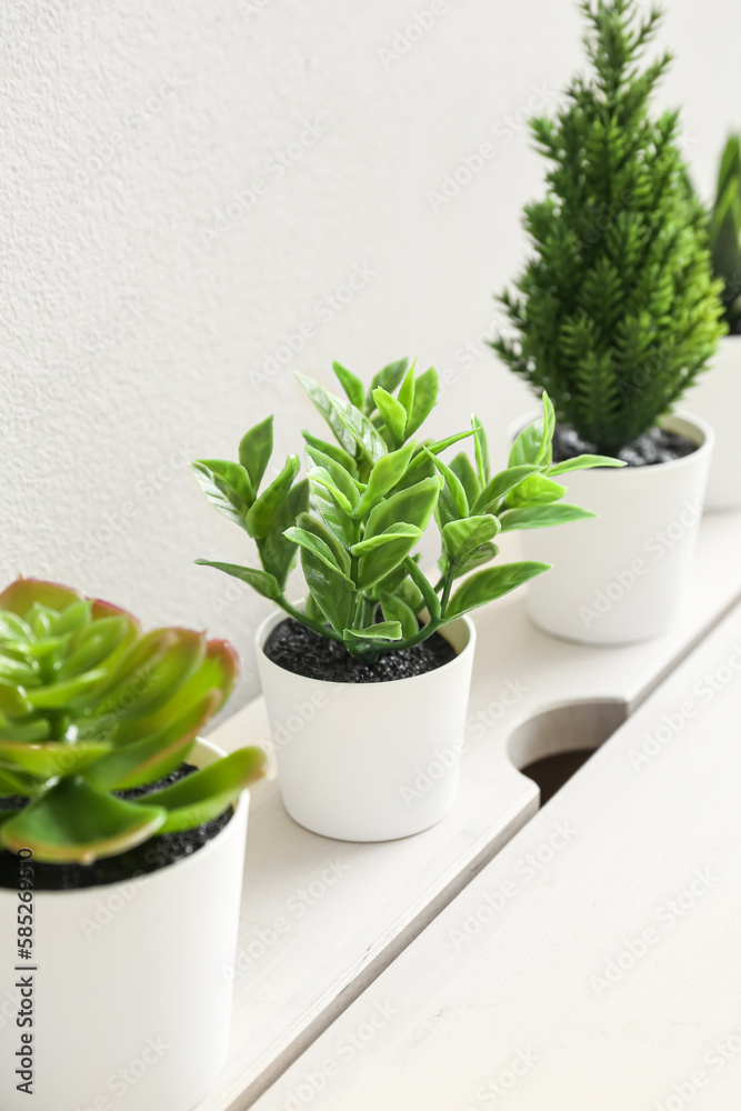 Artificial plants on table near light wall Artificial plants on table near light wall