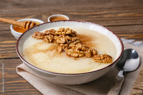 Bowl of tasty semolina porridge with nuts on wooden table