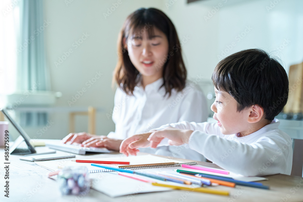 部屋で仕事をする母親と、お絵描きをする子供 部屋で仕事をする母親と、お絵描きをする子供