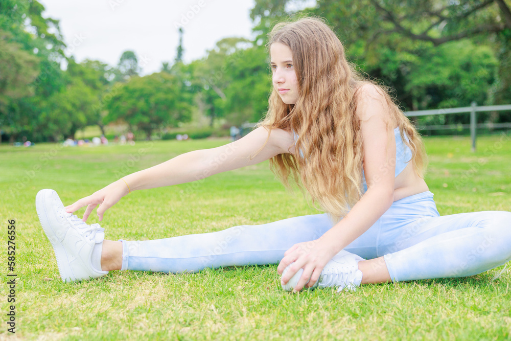 公園の芝生に座りストレッチをするオーストラリアの中学生