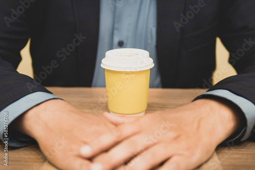 Businessman and paper yellow glass of coffee. Front view. Concept of coffee break.