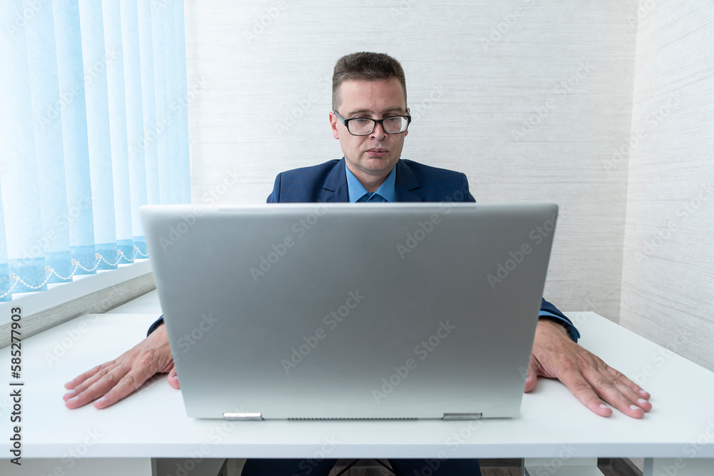 employee looking wearing glasses at computer monitor during working day in office. focused reading of information on a laptop in the office. The manager is at work. employee looking wearing glasses at computer monitor during working day in office. focused reading of information on a laptop in the office. The manager is at work.