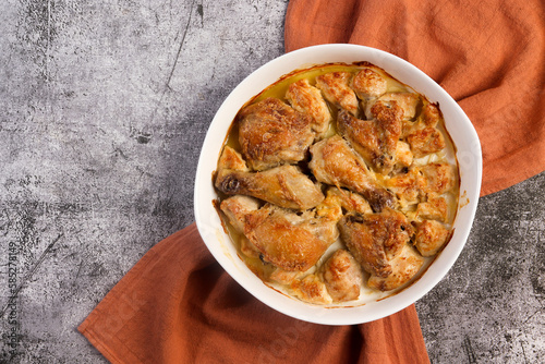 Classic Baked Chicken Pieces in a white baking dish on a dark grey background. Top view, flat lay
