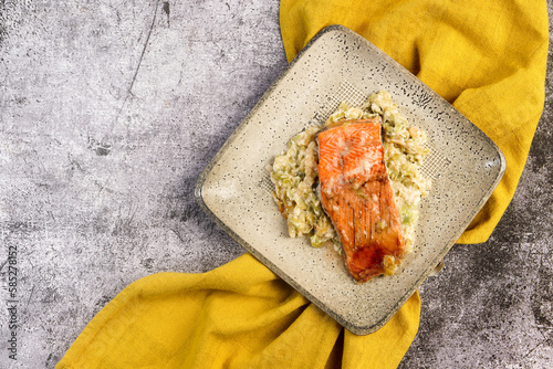 Salmon baked in cream with leeks on a square plate  on a dark gray background. Top view, flat lay