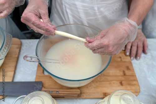 process of making cheese with a pigtail. Hands kneading cheese in milk.